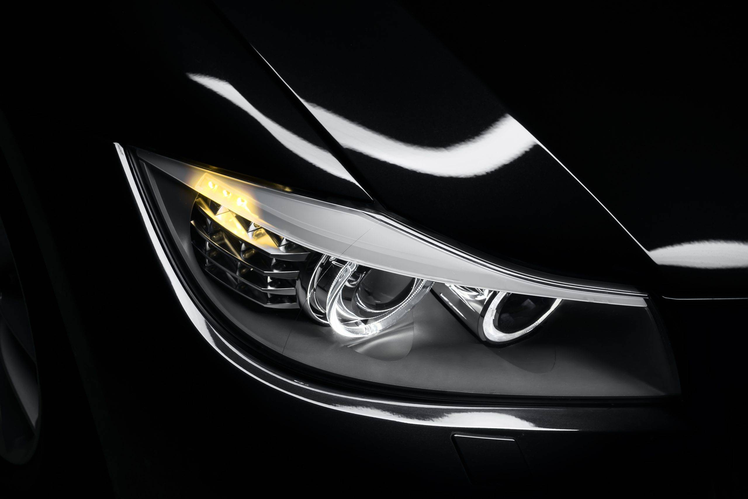 Headlight lamp of black modern car, close-up